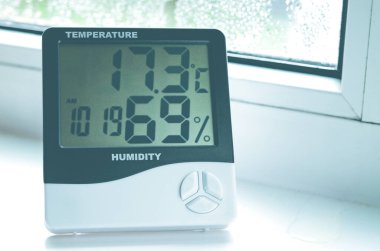 Termometresi olan bir higrometre pencere pervazında buğulanmış duruyor. Plastik pencereler.