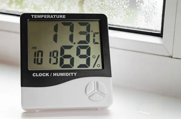 装有温度计的湿度计站在窗台上 带有冷凝 塑料窗户 免版税图库图片