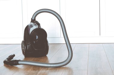 Siyah elektrikli süpürge dairenin zemininde duruyor. temizlik kavramı.