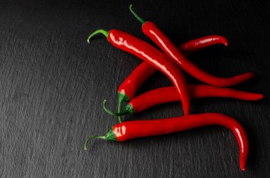 Sebzeler. Baharatlar. Baharatlı kırmızı Meksika biberi siyah bir taşın üzerinde yatıyor.