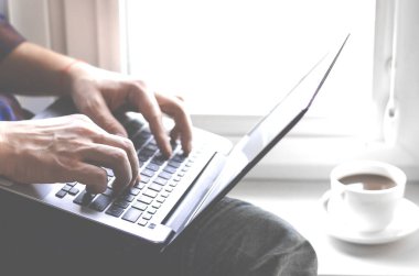 Programcının elleri dizüstü bilgisayarda. Pencere kenarında çalış.