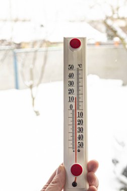 Pencere zemininde kırmızı pullu beyaz termometre. Kış