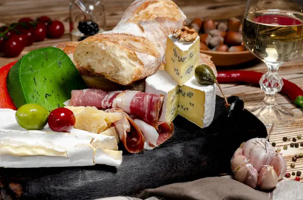 Cheese and cold cuts, olives and baguette on a wooden board. Cold appetizers