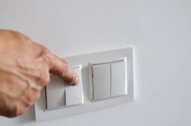 El ışığı yakar. Beyaz bir duvarda beyaz bir anahtar..