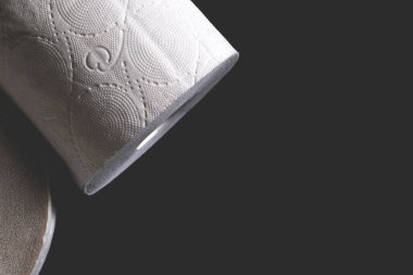 Siyah arka planda duran beyaz tuvalet kağıdı rulosu