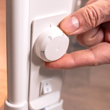 Erkek eli elektrikli ısıtıcının ısısını düzenler. Elektrik enerjisi. Sıcaklık