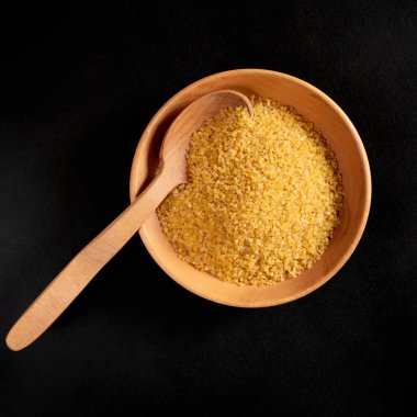 Mısır gevreği. Tahta bir kaşık ve tabakta bulgur. Üst görünüm
