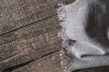 Örülmüş keten peçete eski bir ahşap masanın üzerinde yatıyor. Üst görünüm