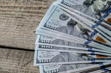 Yeni yüz dolarlık banknotlar eski bir ahşap masanın üzerinde yatıyor. Bir Tuğla Para