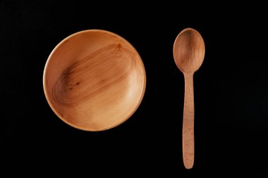 Siyah arka planda kaşık ve plaka. Tahtadan yapılmış çevre dostu çatal bıçak takımı.