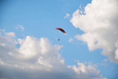 Yazın beyaz bulutlu açık mavi gökyüzü arka planı. Kırsal dağ bölgesinde ekstrem sporlar yapıyor. Yalnız paraşüt. Yaz eğlencesi aktiviteleri. Gökyüzünde sakin bir meditasyon.