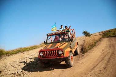 Kırmızı turuncu spor araç, dik dağ tepesinde giden SUV jip. Kırsalda macera gezisi. Doğa koruma. Konsept. Turizm eğlenceli aşırı aktivite. Ukrayna bayrağı