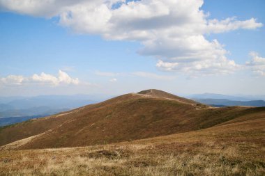 Yazın dağlarda doğal manzara. Parlak mavi gökyüzü ile güneşli kırsal manzara. Doğa koruma kavramı. Açık mavi gökyüzü ve beyaz bulutlarla nefes kesici dağ manzarası.
