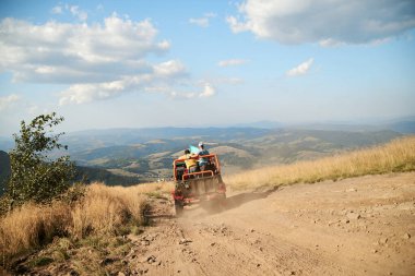 Pylypets / Ukrayna Aug 27 '22::: Kırmızı turuncu spor servis aracı, dik tepede jip sürüyor. Kırsalda macera gezisi. Doğa koruma. Konsept. Turizm eğlenceli aşırı aktivite. Ukrayna bayrağı