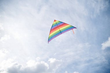 Mavi gri gökyüzünde renkli gökkuşağı uçurtması uçuyor. Mavi arka planda izole edilmiş uçurtma. Hafta sonu eğlence aktiviteleri. Huzurlu bir rahatlama. Sevdiklerinle, çocuklarınla ve ailenle vakit geçir..