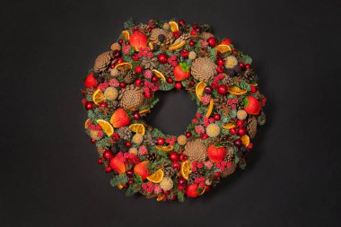 Siyah arka planda renkli bir çelenk. Karanlık yüzeyde meyve ve böğürtlenlerle süslenmiş çelenkler..