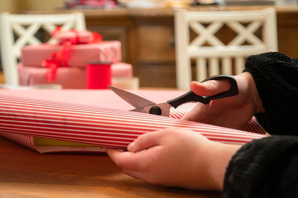 赤いリボンでギフトを包んだ女性 手は赤と白のクリスマスの紙に箱を梱包 — ストック写真