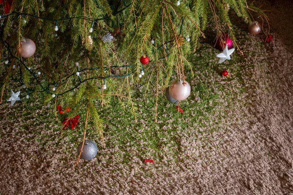 Christmas tree with dried up spikes falling all over the carpet. Dead fir tree, floor covered by thorns after holiday season.