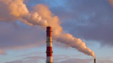 Gün batımında fabrika bacasından zehirli duman bulutları çıkıyor. Hava kirliliği ve eski sanayi enerji santralinin yol açtığı küresel ısınma 