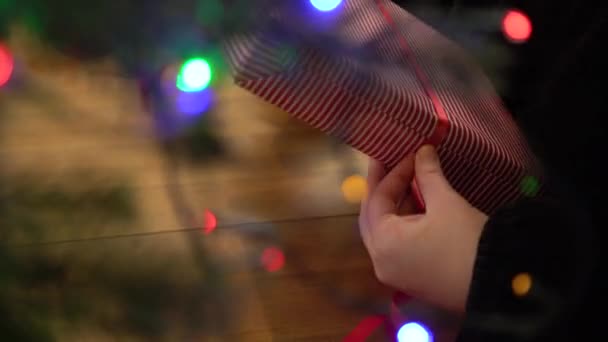 女人用红丝带把礼物用剥光的纸包起来 用红白相间的圣诞纸包着盒子的手 — 图库视频影像