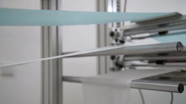 Beyaz ve mavi pamuk lifleri bir fabrikada tıbbi yüz maskesi olarak birleştiriliyor. Solunum maskesi yapan otomatik makineler. 