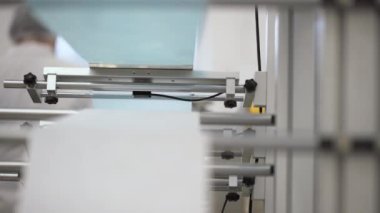 Beyaz ve mavi pamuk lifleri bir fabrikada tıbbi yüz maskesi olarak birleştiriliyor. Solunum maskesi yapan otomatik makineler. 