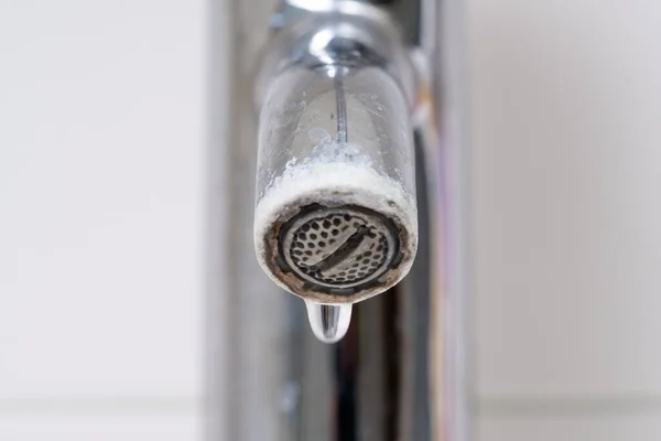 Water drop leaking of a broken tap. Bathroom water leak, corrosion close up.