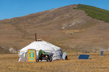 Nomadic persons yurt in rural Mongolian landscape. Ger tent on the foothill with beautiful mountains in the background on the sunny day. clipart