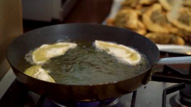 Close up of chefs hand placing Gyoza dumplings with mushroom filling into hot frying pan. Golden crunchy dumplings cooking in oil. 