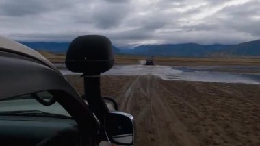 Khovsgol, Moğolistan - Eylül 2022 - SUV aracı dağ nehrinden geçiyor ve Moğol çölünde av gezisine çıkıyor.. 