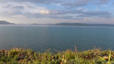 Arka planda güzel dağlar olan Khovsgol Gölü 'nün görkemli manzarası. Ufukta sisli görünen gökyüzü ile mavi su kenarı. 