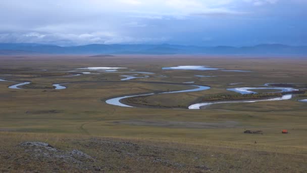モンゴルの草原の壮大な風景です 曇りの日に谷を蛇行川の高高度空中ビュー 背景に山 — ストック動画