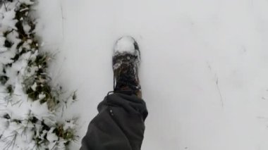 Man walking on a snow path in the forest. Hiking outdoors on a cold winter day. 