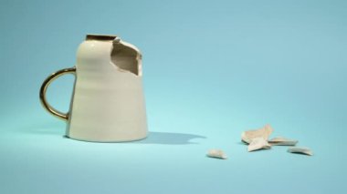 Broken tea cup isolated on blue background. Cracked coffee mug and fragile ceramic pieces 