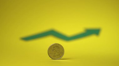 Quarter dollar coin on yellow backdrop. Blurred green arrow in the background. Saving money for the future. 