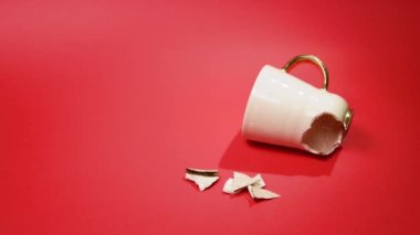 Broken tea cup isolated on red background. Cracked coffee mug and fragile ceramic pieces 