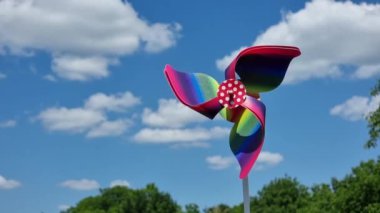 Beyaz bulutlu mavi gökyüzüne karşı renkli fırıldak oyuncağı.