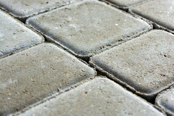 Background from a gray sidewalk path. Close-up of concrete paving slab bricks.