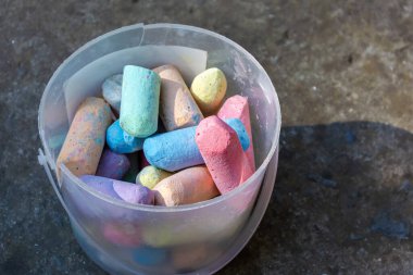 Beton bir arka planda kırık bir kovadaki çok renkli boya kalemleri. Yakın plan..