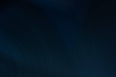 Parlak yıldızlar, sakin bir gece gökyüzünde parıldıyor. Huzurlu kırsal bölgede hafif bir parıltı yayıyor. Ağaçların siluetleri uzaklardan görülebiliyor..