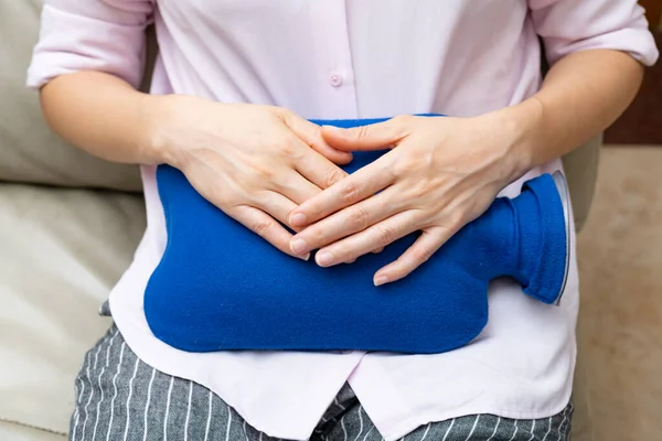 stock image lady holding a hot water bag on the stomach