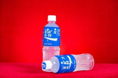 ZHONGSHAN GUANGDONG Çin - 17 Aralık 2022: Kırmızı arka plan yatay kompozisyonu üzerinde iki şişe Pocari teri.