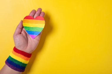 man with LGBT rainbow wrist band and paper heart