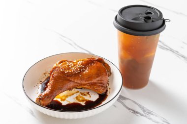 Açılı görünüm yatay kompozisyonda bir fincan limon çayıyla haşlanmış tavuk budu çubuğu.