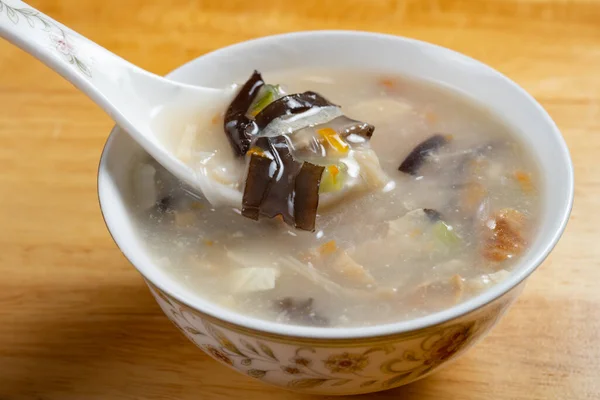 stock image angle view spoon with shredded fish soup with carrot slices and black fungus