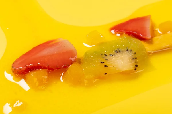 angle view yellow peach flavor with kiwi and strawberry slices popsicle melted on yellow background