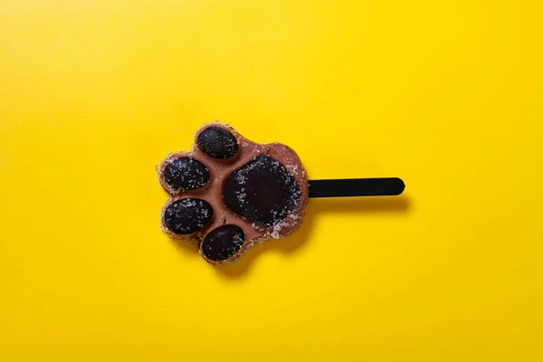 top view bears paw shape chocolate flavor popsicle on yellow background