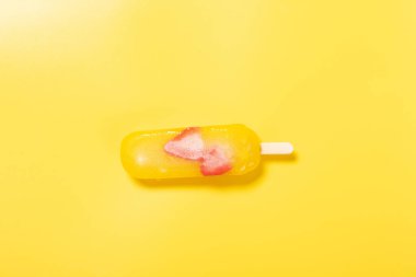 Çilek dilimli mango aromalı buzlu dondurma sarı arka planda erimeye başlar.