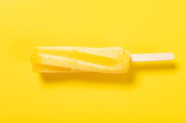 Sarı arka planda taze, bükülmüş ananas aromalı dondurma.