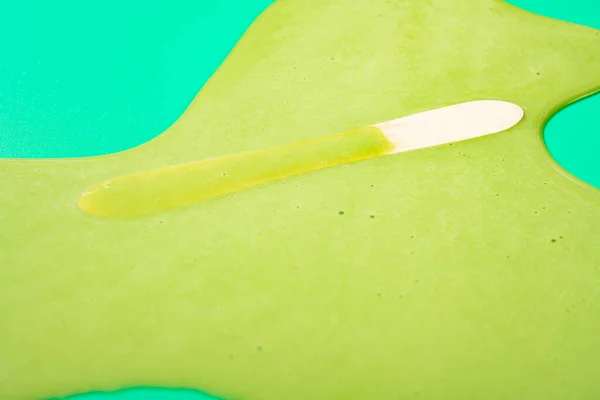 angle view melted matcha and milk flavor popsicle on green background